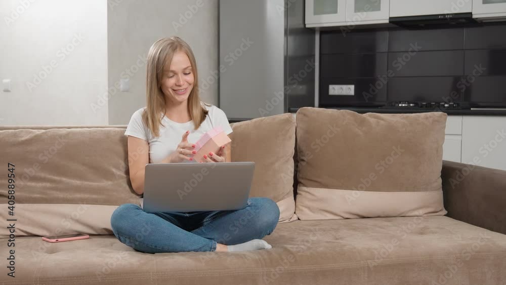 Positive lady opening gift box during video call on laptop Positive lady opening gift box during video call on laptop