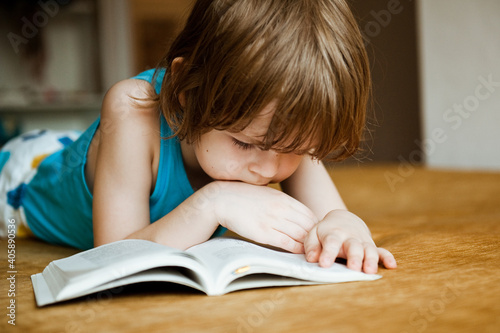 A child reads a book. The boy is lying on the sofa and reading a book.