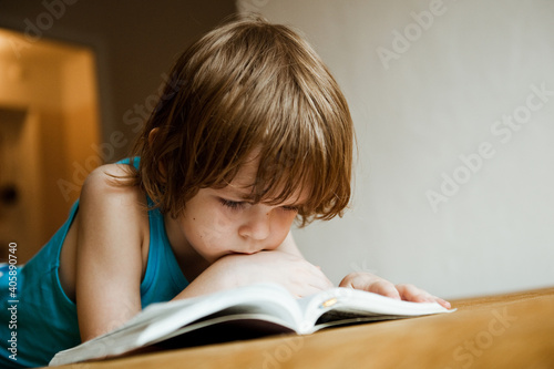 A child reads a book. The boy is lying on the sofa and reading a book.