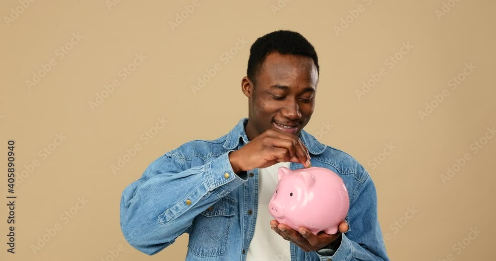 Man inserting coin into piggy bank over beige background
