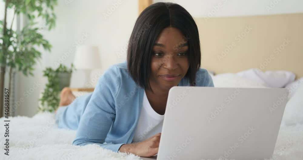 Happy woman using laptop lying on bed at home Happy woman using laptop lying on bed at home