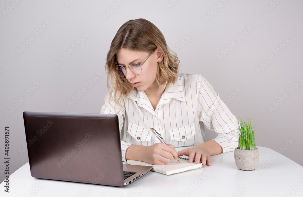 Young woman using laptop and writing something in a notebook Young woman using laptop and writing something in a notebook