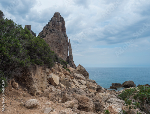 View of Pedra Longa, limestone rock pillar at coast Gulf of Orosei, beginning of the famous and difficult hiking climbing trail Selvaggio blu, wild blue, Sardinia, Italy