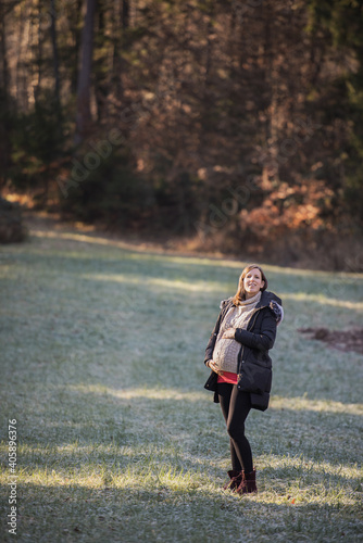 Happy young pregnant woman standing outside in nature