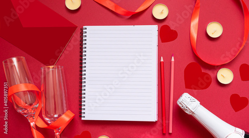 Mockup notepad close-up, envelope, hearts, ribbon, candles, champagne on a red background. Concept of writing love letters or invitation for valentine's day. copy space. Flat lay. top view