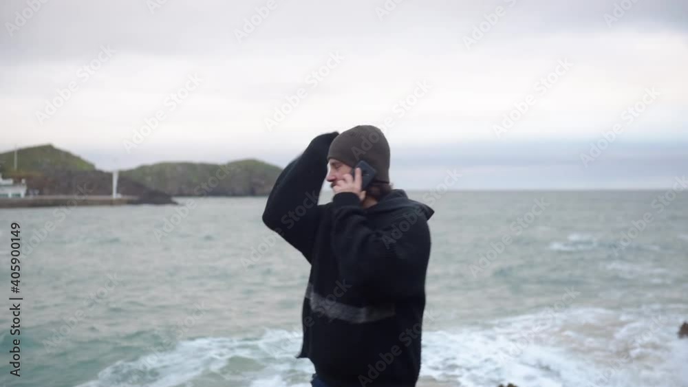 very angry bearded man arguing and quarreling in a conversation on the phone with the sea in the background. relationships and communication. very angry bearded man arguing and quarreling in a conversation on the phone with the sea in the background. relationships and communication.