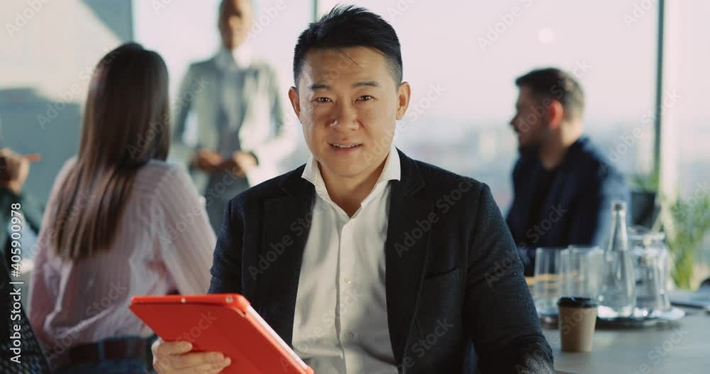Face of handsome susccessful chinese asian young businessman holding tablet computer attending corporate meeting in office company. Multi-ethnic people. Face of handsome susccessful chinese asian young businessman holding tablet computer attending corporate meeting in office company. Multi-ethnic people.