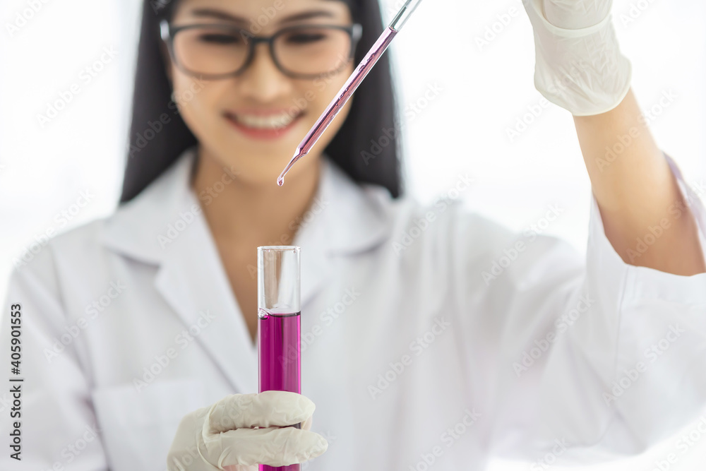 Young Asian scientist woman holding and looking at the chemical flasks in the laboratory Young Asian scientist woman holding and looking at the chemical flasks in the laboratory