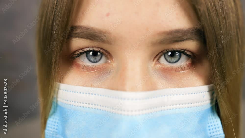 Beautiful young woman with blue eyes wearing medical mask and looking at you Beautiful young woman with blue eyes wearing medical mask and looking at you
