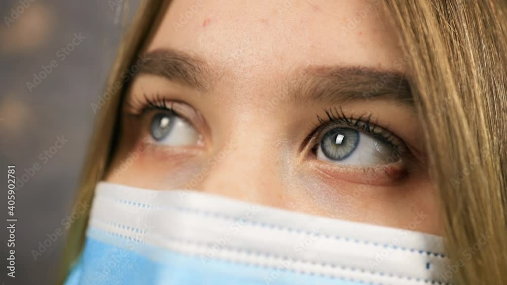 Macro eye view: Beautiful young woman with blue eyes wearing medical mask and looking away Macro eye view: Beautiful young woman with blue eyes wearing medical mask and looking away