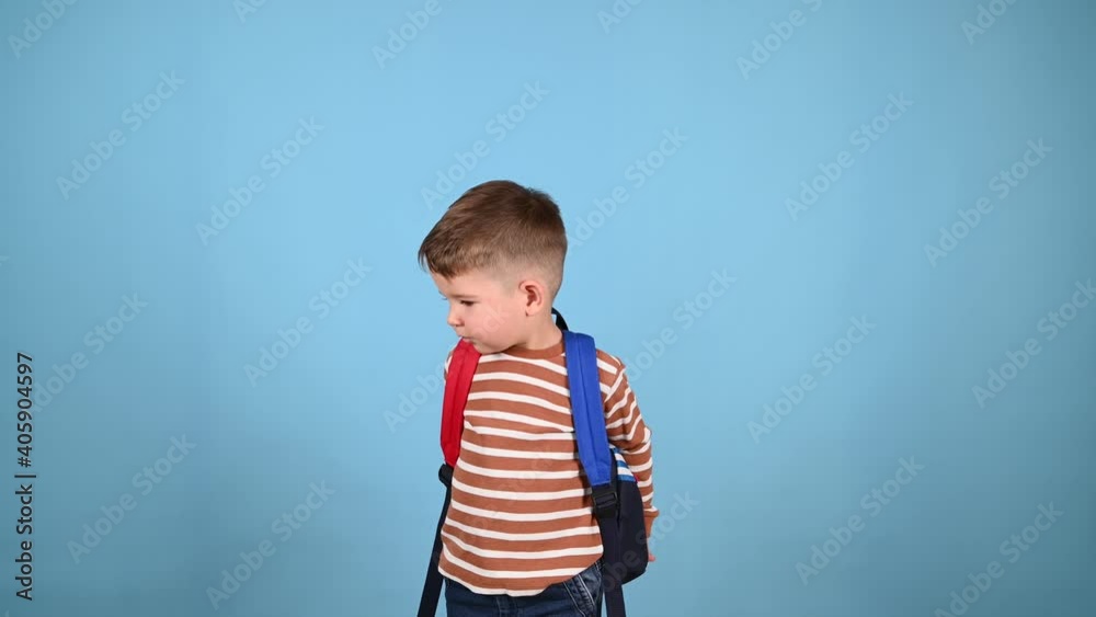 Caucasian toddler boy with a backpack on a blue background. Portrait of little smilling schooler. Learning activities for toddlers Caucasian toddler boy with a backpack on a blue background. Portrait of little smilling schooler. Learning activities for toddlers