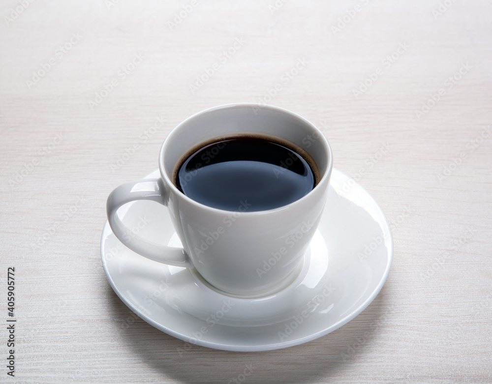 white cup with black coffee and saucer on the table