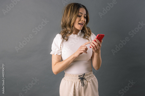 joven mujer adulta con sonrisa utiliza teléfono inteligente mensajería instantánea aislada