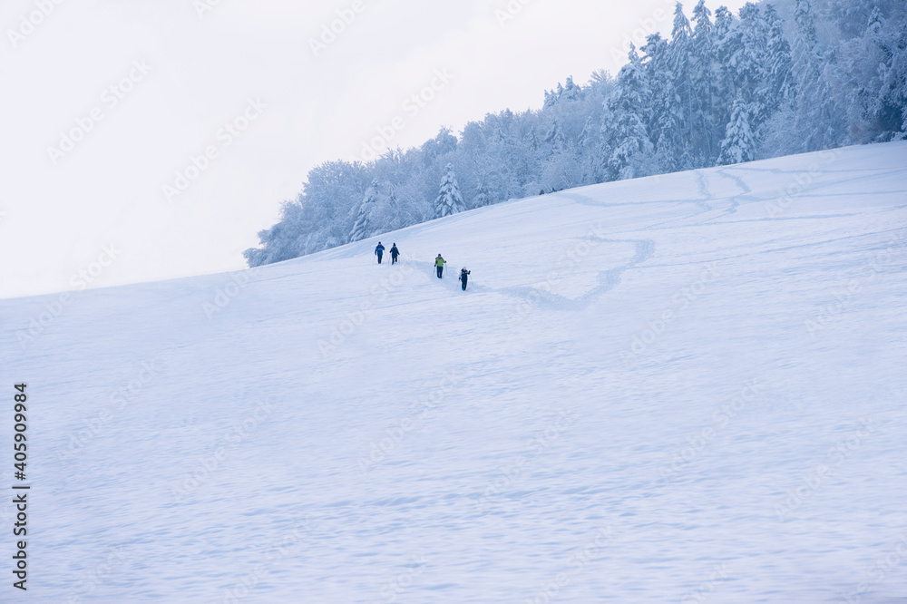 Wintersportler, Schneeschuhwanderer und Spaziergänger laufen durch eine sehr verschneite Landschaft in der Abenddämmerung