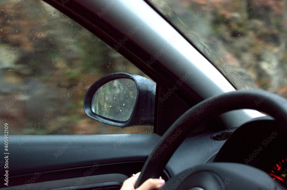 Hands of white woman car on rainy autumn or winter day driving on the road