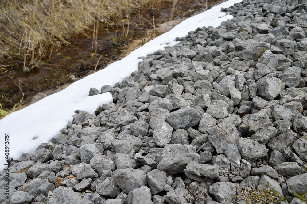 Gray natural rubble close-up on the dam against the background of the drainage channel. Background