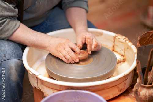 Pottery workshop. A cut-off image of a potter working with clay on a potter's wheel.