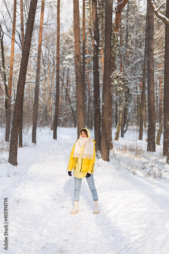 Beautiful young cheerful woman in a snowy landscape winter forest having fun rejoices in winter and snow in warm clothes, scarf and jeans © Анастасия Каргаполов