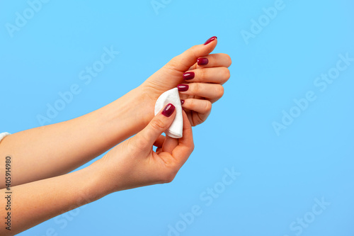 Female hand holding cotton discs against blue background