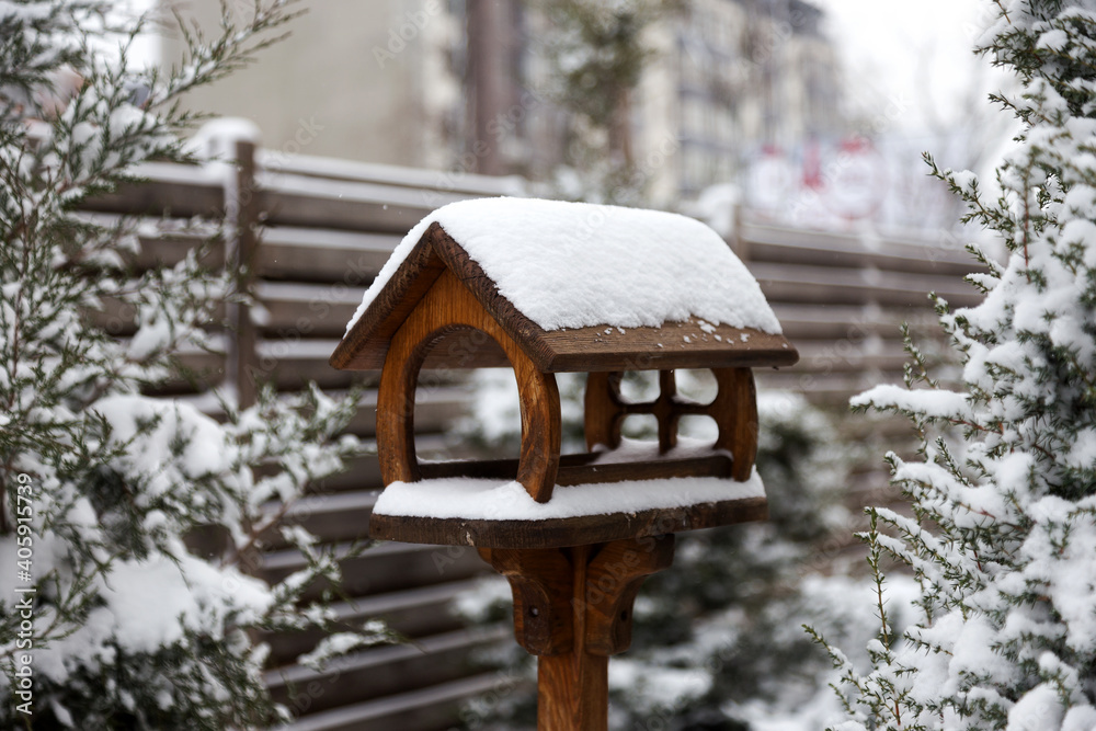 Snow-covered bird feeder in the courtyard of a village house on cloudy winter day. Snow-covered bird feeder in the courtyard of a village house on cloudy winter day.