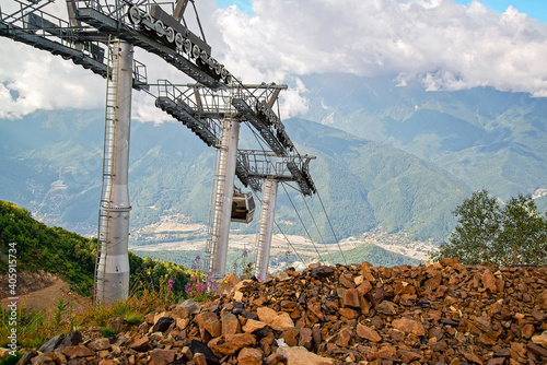 View of the mountains, overgrown with dense deciduous and coniferous forests, with modern transport, including lifts for mountain skiers and economic communications for the active recreation of people