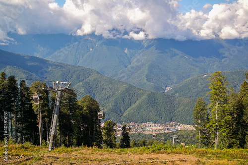 View of the mountains, overgrown with dense deciduous and coniferous forests, with modern transport, including lifts for mountain skiers and economic communications for the active recreation of people