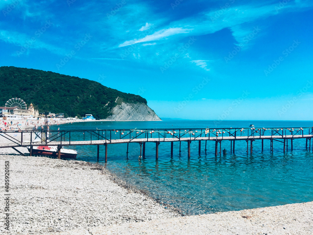 Pier which goes into the blue sea on a bright sunny day