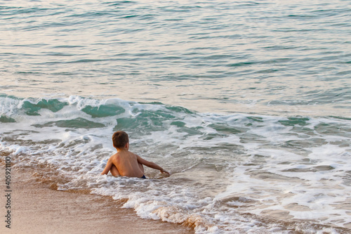 Little boy learn to swim by the sea. Active lifestyle. Weekends, holidays. The child sits on the waves.