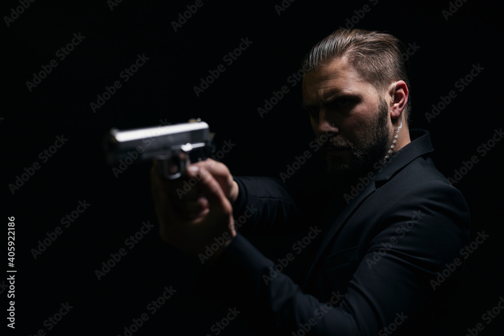Real bandit in black suit aiming with gun over black studio background. Concept of danger and mafia. Criminal type man. Real bandit in black suit aiming with gun over black studio background. Concept of danger and mafia. Criminal type man.