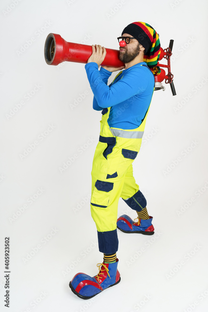The clown firefighter holds a fire pump in his hands like a grenade launcher.