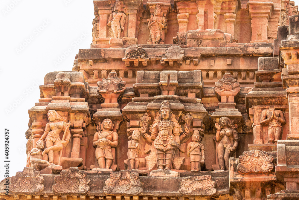 Hampi, Karnataka, India - November 5, 2013: Vijaya Vitthala Temple. Closeup of 2 statues rows on red stone Gopuram under silver sky.