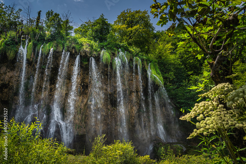 Streaks of water coming down from lichens hooked at tall waterfall. Green lush forest in Plitvice Lakes National Park UNESCO World Heritage  Croatia