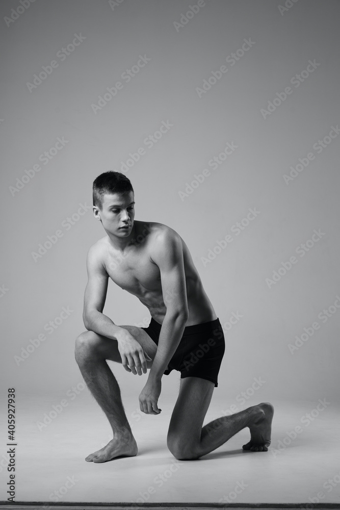 Naklejka premium black and white photo of an athlete indoors in full growth on one knee
