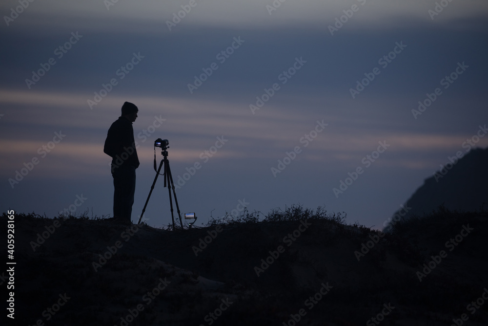 silhouette of photographer at sunset with the dark blue sky in the background