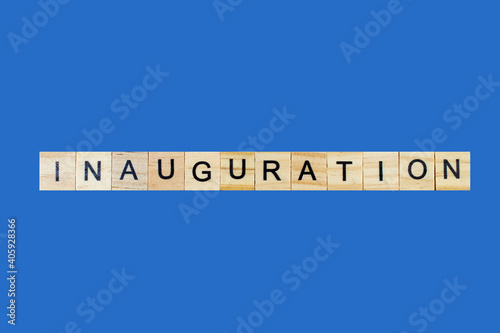 Inauguration . English word on blue background composed from letters on wooden cubes. Learning english concept.