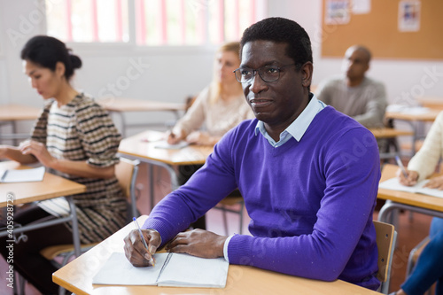 Portrait of young adult male studying in classroom with colleagues