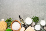 Spa product composition with cosmetics, sea salt, towel and palm leaves at stone table. Top view image with copy space.