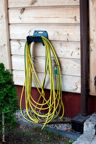 Yellow and green striped garden hose hung on a hook. Spala Poland