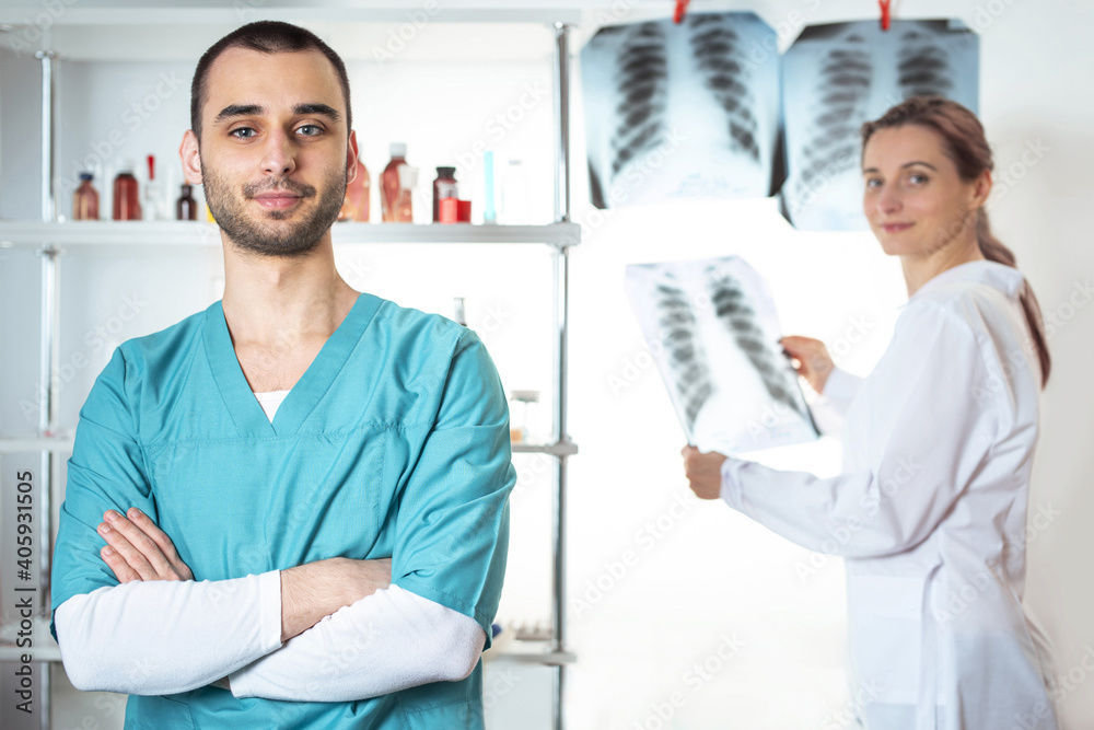 Obraz premium Two doctors. Woman in white lab coat holding at x-ray and man in medical apparel holding. Lifestyle outdoor scene