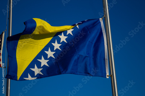 A Bosnian flag on a pole waves in the wind on a sunny day. photo