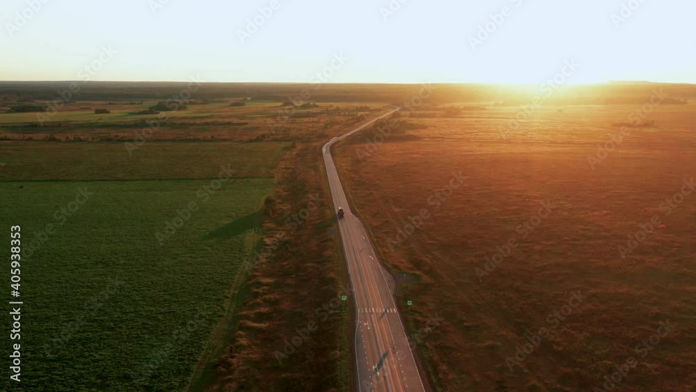 Aerial view of a car driving at sunset in the countryside in summer Aerial view of a car driving at sunset in the countryside in summer