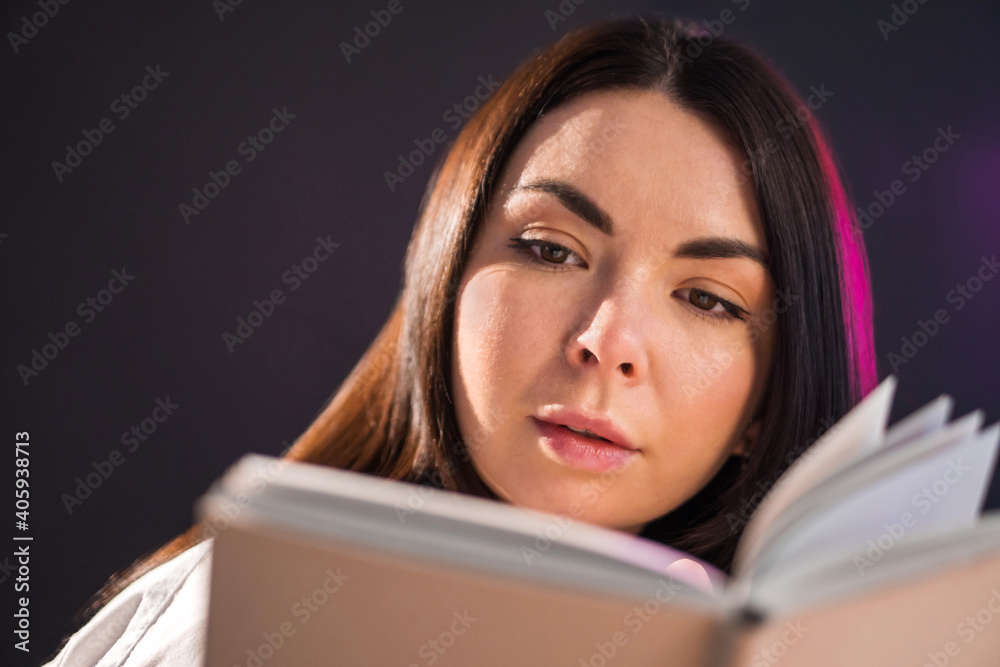 Young brunette girl is reading exciting book over black background. Young brunette girl is reading exciting book over black background.