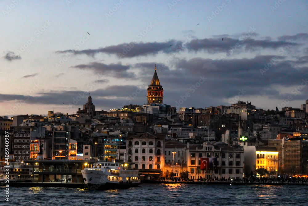 Fototapeta premium Motion blur view of İstanbul cityscape at dusk. Amazing capture of Galata Tower and old buildings around it with lights in the evening.