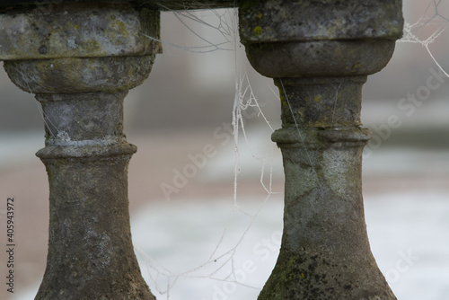 A stone balustrade on a winters morning with rozen cobweb