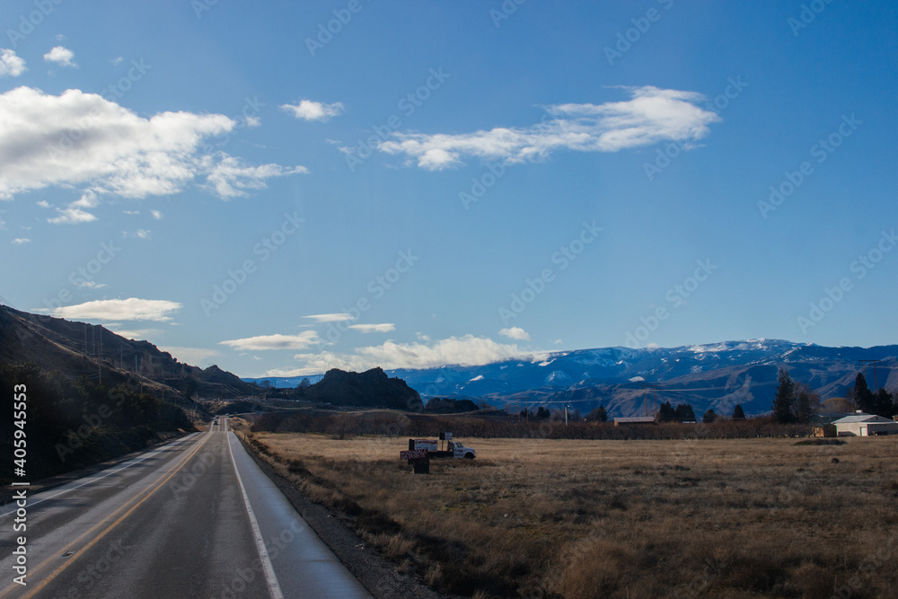 Autumn landscape with a highway among the mountains against the background of a blue sky and blue mountains in front, Washington state, USA