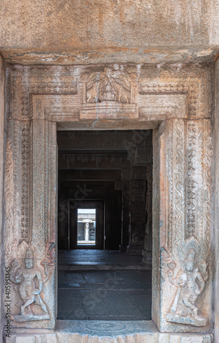 Hampi, Karnataka, India - November 5, 2013: Vijaya Vitthala Temple. Looking through the brown stone doorway into darker sanctum. Vishnu sculptures in door frame. Lakshmi fresco on top.
