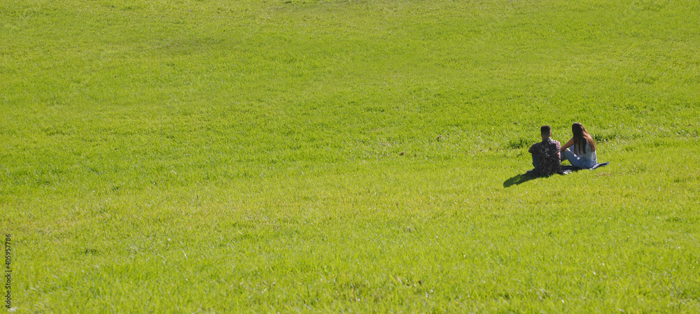 Casal de namorados sentados na erva no meio de um campo aberto me momento romântico