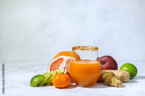 Healthy eating  healthy lifestyle. Multifruit juice from fresh fruit. Fruit around a glass of juice. Fresh fruit  grapefruit  mandarins  limes  apple  ginger. Bright background with place for text.
