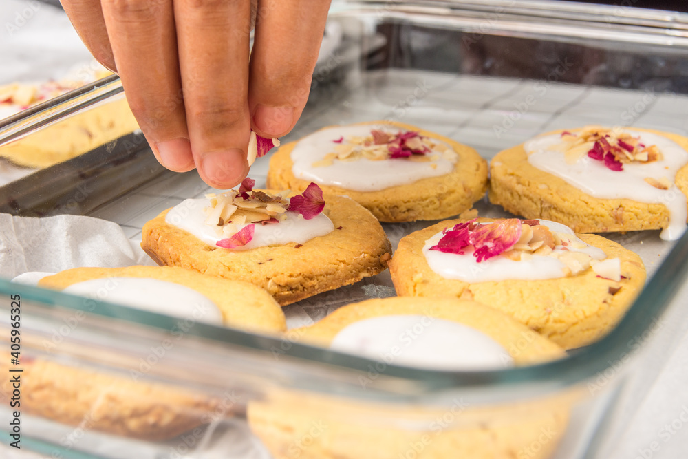 Close up image of finishing touches being added to home made cookies with vanilla and rose petal topping Close up image of finishing touches being added to home made cookies with vanilla and rose petal topping