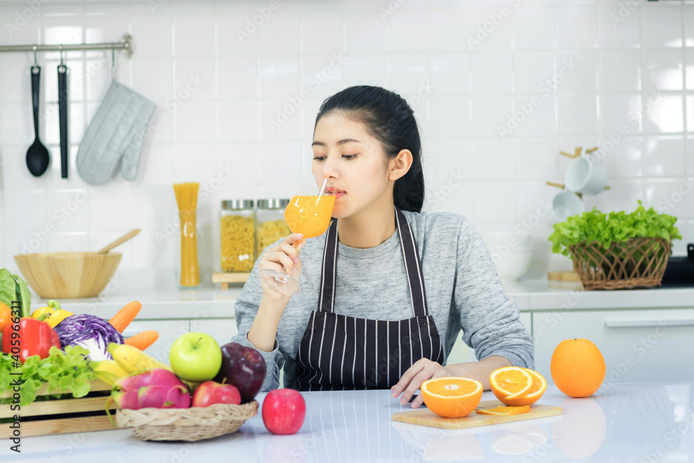 Asian women taking care of health and body shape Preparing food in the kitchen and waiting to drink orange juice in the glass.
Asian women taking care of health and body shape Preparing food in the kitchen and waiting to drink orange juice in the glass.